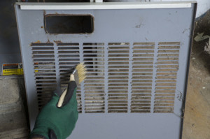 Technician Cleaning Front Cover Of Furnace